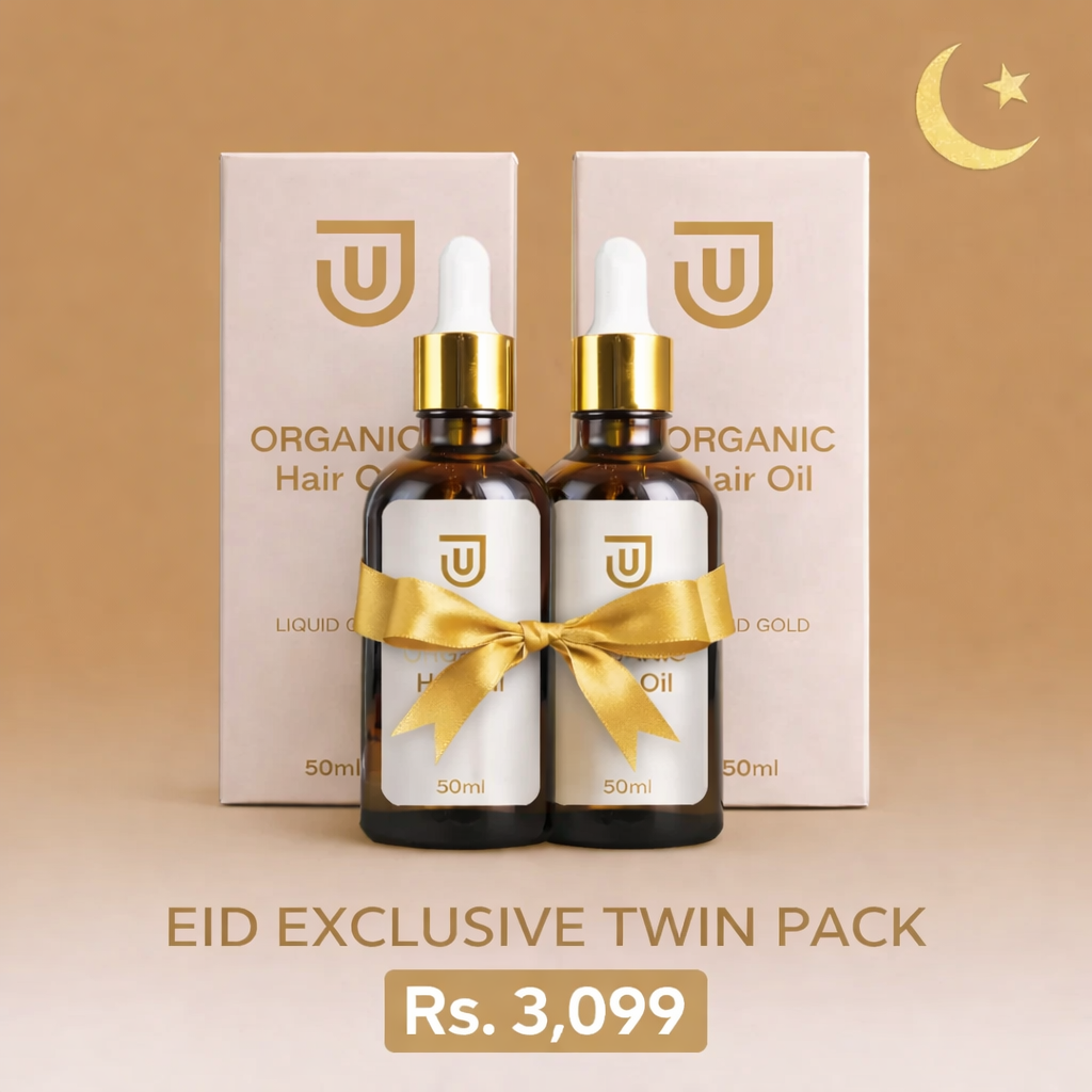Two bottles of organic hair oil with a gold bow and packaging on a beige background.